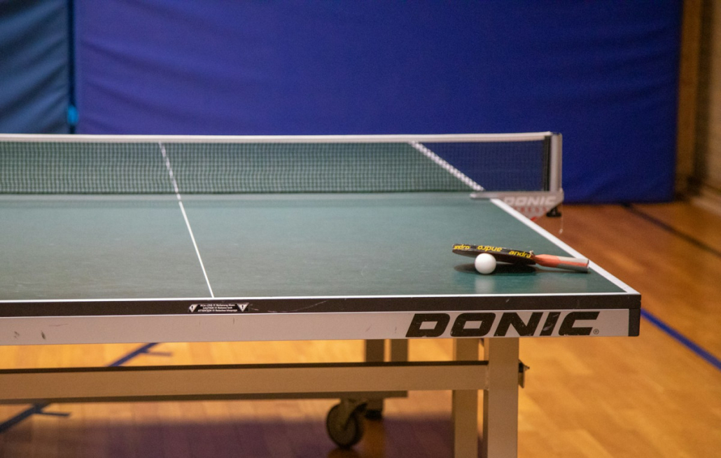 Tischtennisplatte mit Schläger und Ball in einer Sporthalle