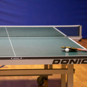 Tischtennisplatte mit Schläger und Ball in einer Sporthalle